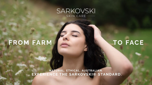 Woman with radiant skin in a wildflower field, eyes closed and hand in hair. Text says “FROM FARM TO FACE” and “Experience the SARKOVSKI® Standard. Natural. Ethical. Australian.”