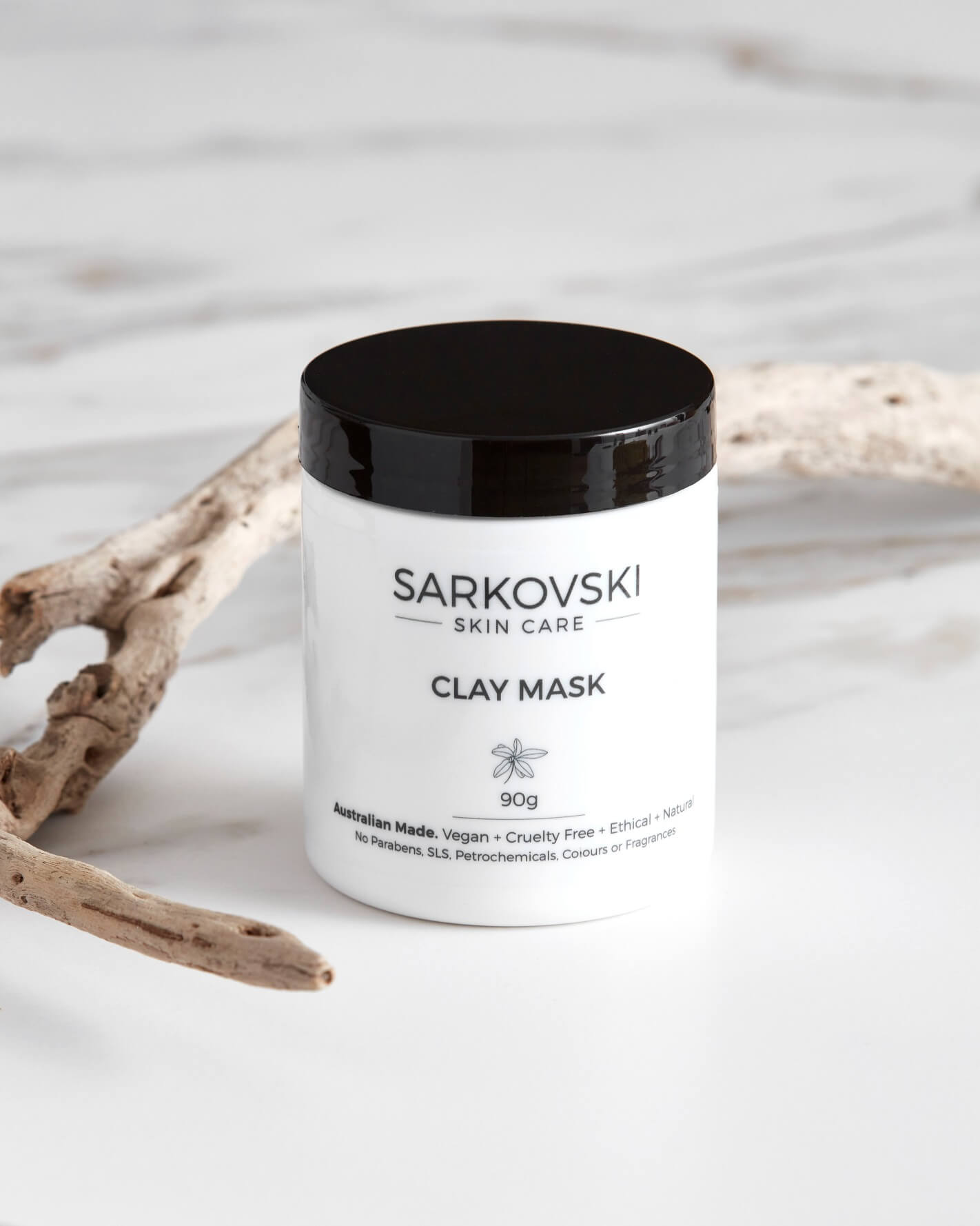 SARKOVSKI® Clay Face Mask 90g – natural Australian skincare; together with dried wooden stick neatly arranged on top of marble table.  SARKOVSKI® Clay Face Mask is formulated to purify, nourish, and revitalise your skin.